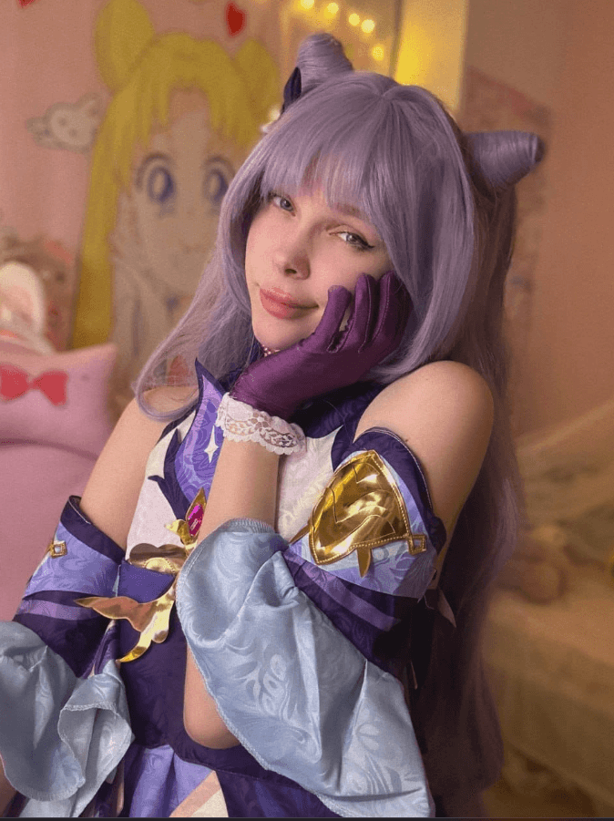 Cosplayer wearing a lavender wig and horn headband, donning purple and blue armor, posing with a hand on the cheek.